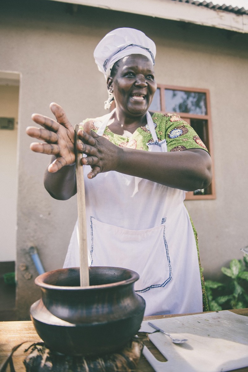 A cook preparing a pot of food outside her kitchen