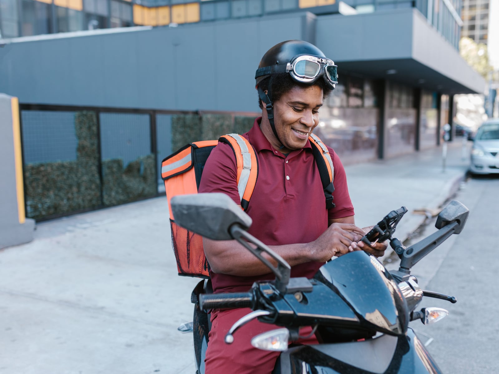 A delivery rider on his motorbike checking his phone